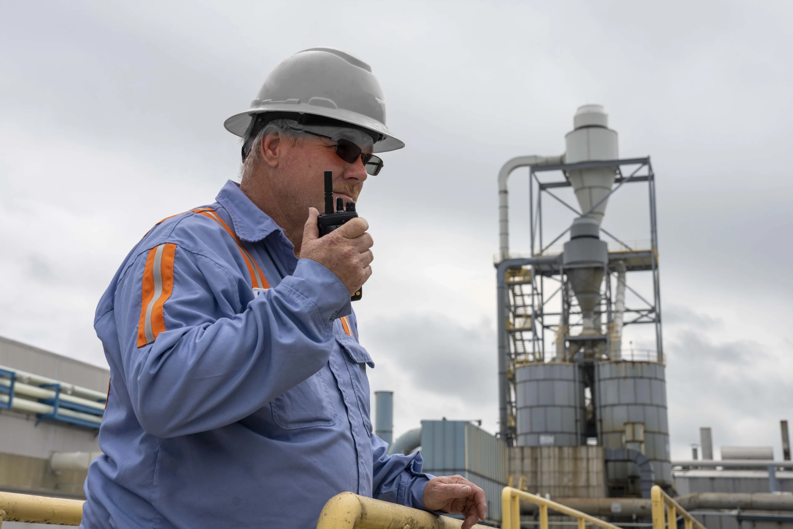 a man in a hard hat talking on a walkie talkie La Guía Completa de Radios Motorola DMR